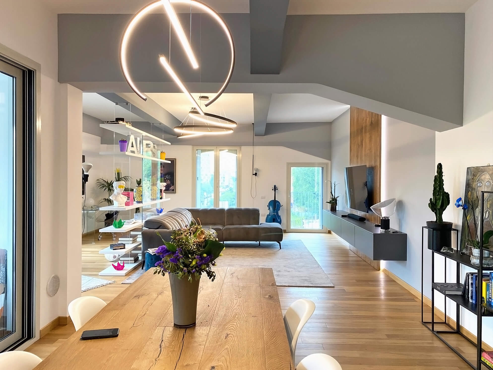 L'open space con il tavolo da pranzo in legno, il soggiorno e la luce delle finestre sul parquet