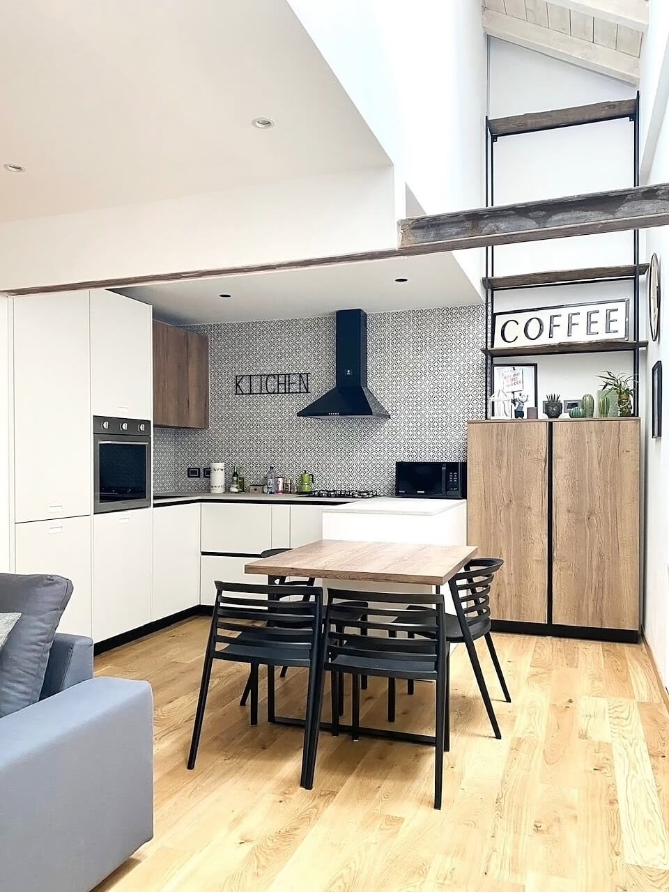 Cucina bianca e legno con il tavolo da pranzo, sotto la doppia altezza